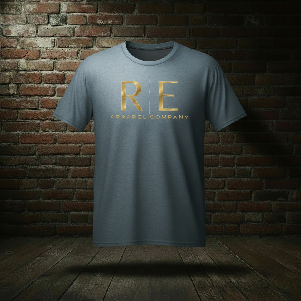 Rogue Standard Gold Tee in Stonewashed Blue on a ghost form against a dark brick wall and wood floor